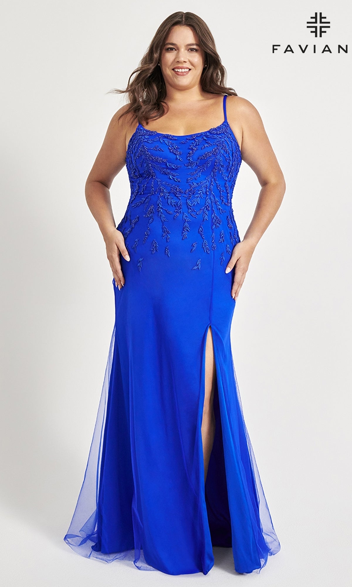 A woman wears the Faviana Plus-Size Beaded Long Formal Dress 9559 in royal blue, featuring thin straps, beaded details, a thigh-high slit, and floor-length styling against a plain background.